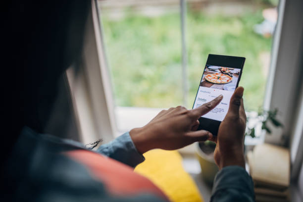 black woman in her home, ordering food online through a mobile app on her phone